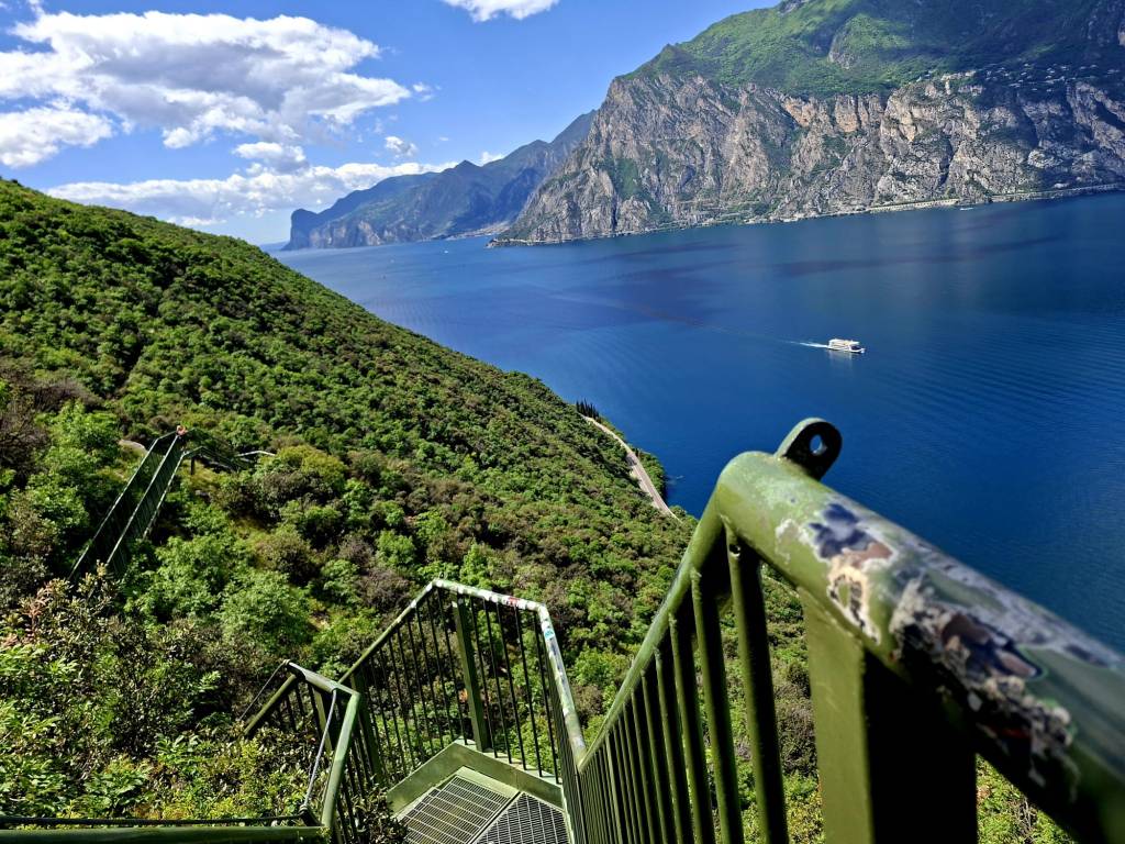 Spektakuläre Metalltreppen auf dem Busatte-Tempesta Wanderweg oberhalb vom Gardasee mit Panoramablick auf See, Berge und Felswand.