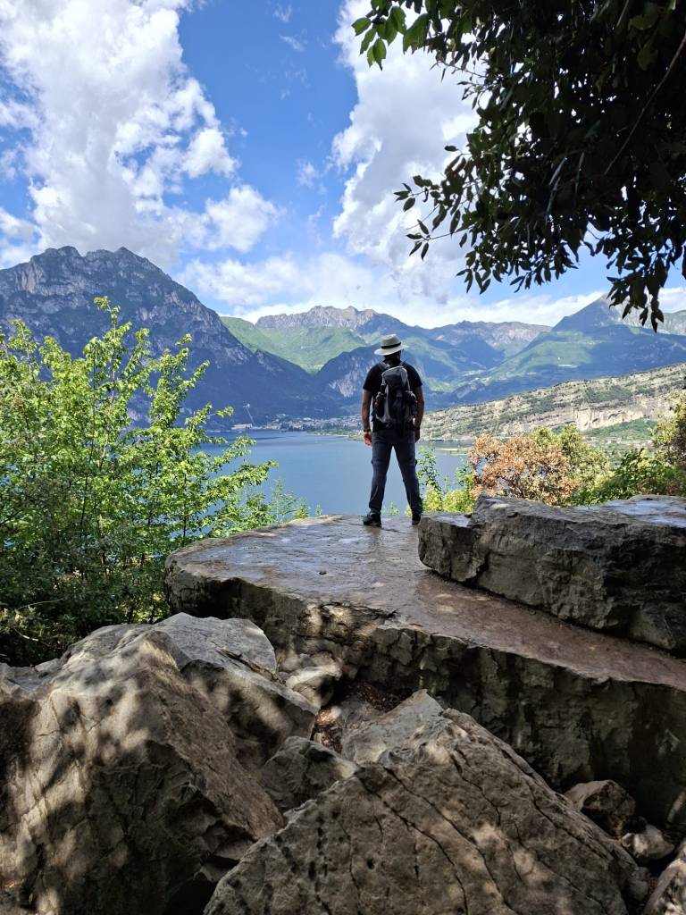 Aussichtspunkt am Busatte-Tempesta Wanderweg oberhalb vom Gardasee mit Wanderer, Felsen, Bergen und weitem Panoramablick über den See.
